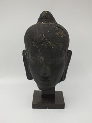 une image représentant une statue d'une tête posée sur un socle en bois