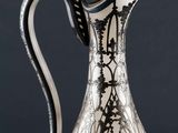 an antique silver and black glass pitcher sitting on top of a table