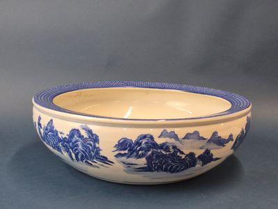 a blue and white bowl with a mountain scene on it