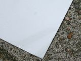 a white piece of paper on the ground next to a brown piece of paper