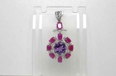 un pendentif en amethorate et saphir rose présenté dans une vitrine transparente