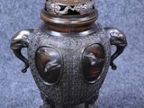 an image of a metal urn with a bird on top of it