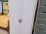 un réfrigérateur blanc posé à côté d'un lit dans une chambre