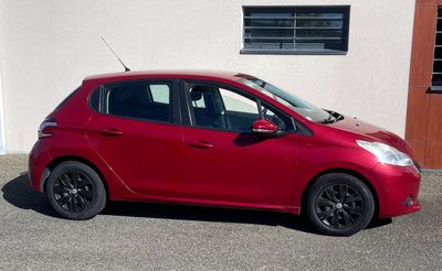 une petite voiture rouge garée devant un immeuble