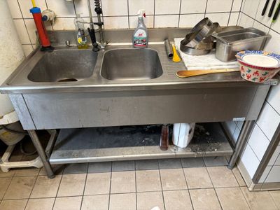 a sink in a kitchen with a lot of clutter on the floor