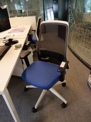 un bureau d'ordinateur avec une chaise bleue et un écran posé dessus
