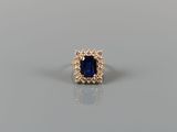 a blue sapphire and diamond ring on a gray surface