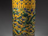 yellow vase with blue and green designs on it sitting on a table
