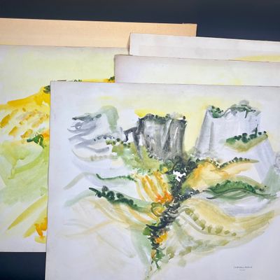 trois aquarelles représentant des montagnes et des arbres, posées sur une table