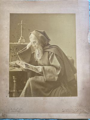 an old photo of a man sitting at a table reading a book