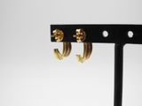 a close up of a pair of gold hoop earrings on a black stand