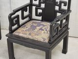 a black chair with a cushion on it in front of a white wall
