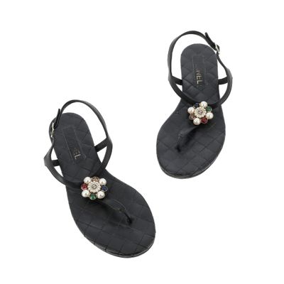 une paire de sandales noires ornées de perles sur les orteils