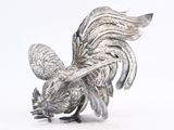 a silver statue of a rooster on a white surface