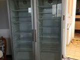 two empty refrigerators in a room with a tile floor
