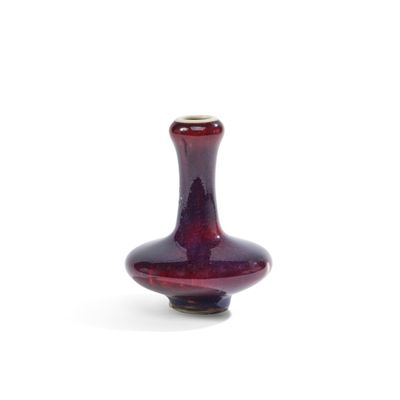 un vase en verre rouge posé sur une surface blanche