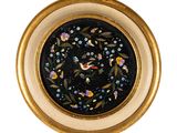 une assiette noire et dorée ornée d'un oiseau et de fleurs