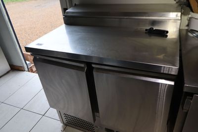 un plan de travail en inox avec un réfrigérateur en arrière-plan