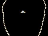 un ensemble composé d'un collier et d'une bague en perles blanches, sur fond noir