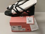 des chaussures à talons hauts noires et blanches posées sur une boîte rose avec une étiquette de prix