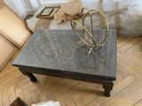 une table basse avec un plateau en marbre posée sur un parquet en bois massif