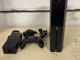La Xbox One est posée à côté d'une manette de jeu et d'un chargeur