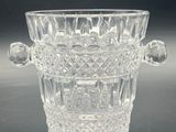 a clear glass vase with a handle on a table