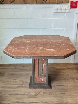 a small table with a red marble top on a wooden floor