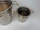a silver pot and a silver cup on a white table