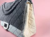 grey and white quilted handbag with chain strap on pink background
