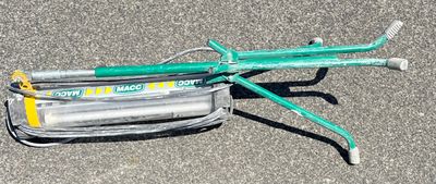 a green hose laying on the ground next to a green lawn mower