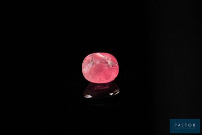 un diamant rose sur une surface noire, dans l'obscurité