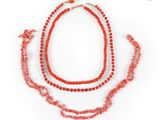 a close up of a necklace with red beads on a white background