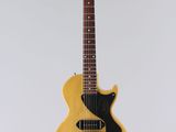 une guitare électrique jaune accrochée à un mur blanc