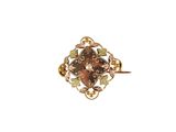 une image représentant une bague en or sertie d'une pierre marron et entourée de feuilles