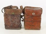 two old leather bags sitting side by side on a white surface