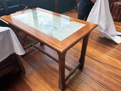 une table avec un plateau en verre posée sur un parquet