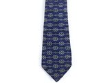La cravate est bleue et dorée, avec un motif de cercles.