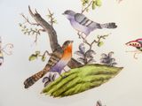une assiette sur laquelle sont peints des oiseaux et des papillons