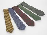quatre cravates de couleurs différentes sont alignées sur une surface blanche