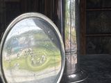 a silver vase sitting on a table with a mirror on it