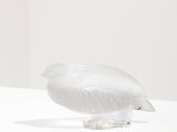a glass sculpture of a bird sitting on a white surface
