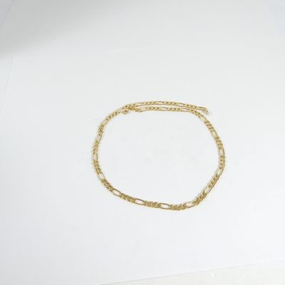 Le bracelet en chaîne d'or est posé sur une feuille de papier