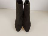 une paire de bottines en daim noir posées sur une surface blanche