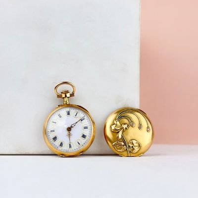 une montre de poche en or posée à côté d'un bloc de marbre blanc