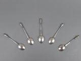 six silver spoons are arranged in a circle on a gray surface