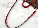 a red and brown handbag sitting on a white surface