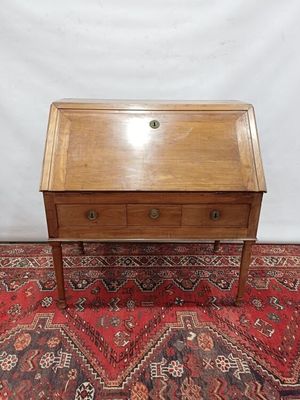 un petit bureau en bois avec des tiroirs, posé sur un tapis