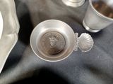 a silver plate with a coin on it next to a silver cup