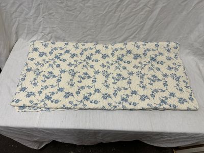 nappe à motifs floraux bleus et blancs posée sur une nappe blanche